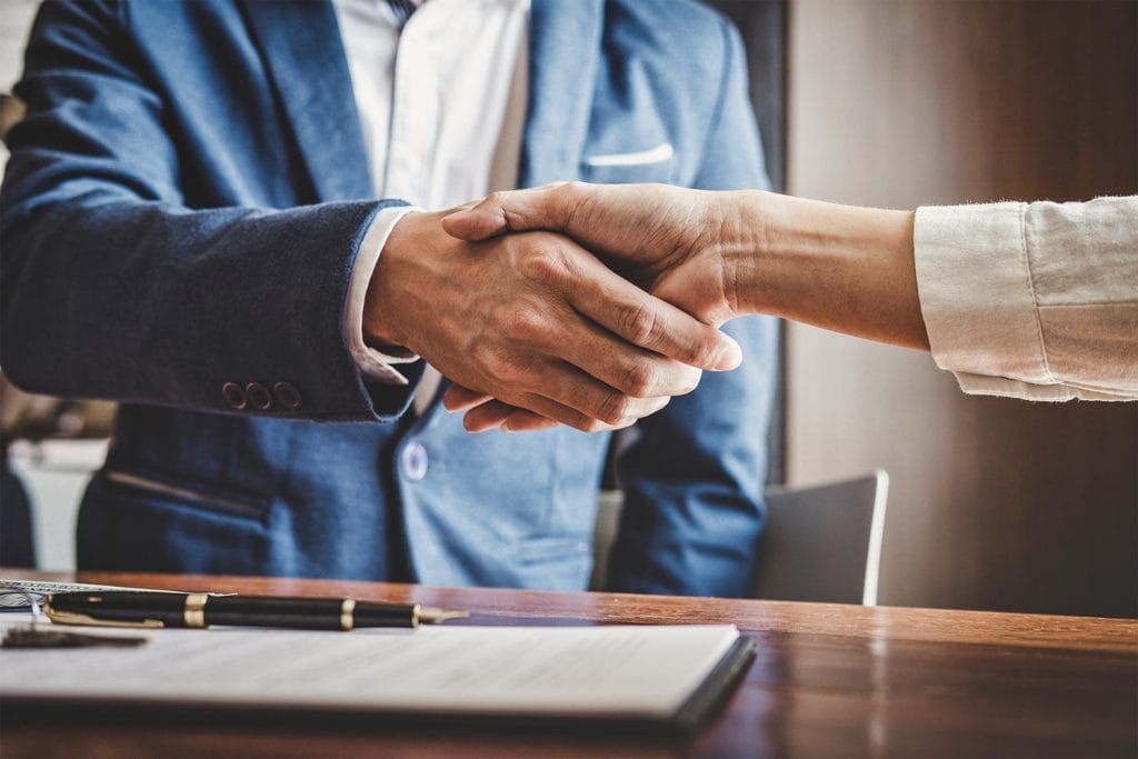 Investment capital: close-up of two hands shaking over a desk with a document and pen